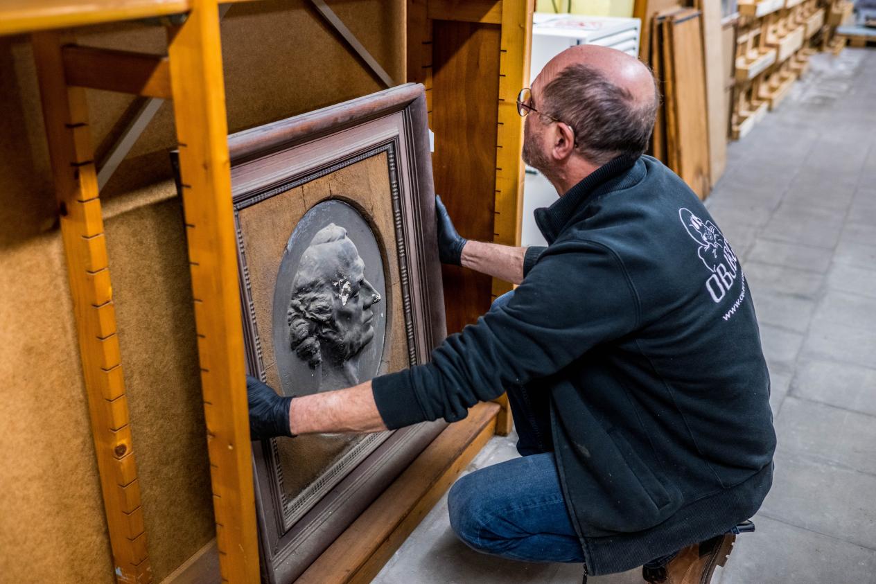 Een medewerker van Object Care neemt voorzichtig een beeld van het rek