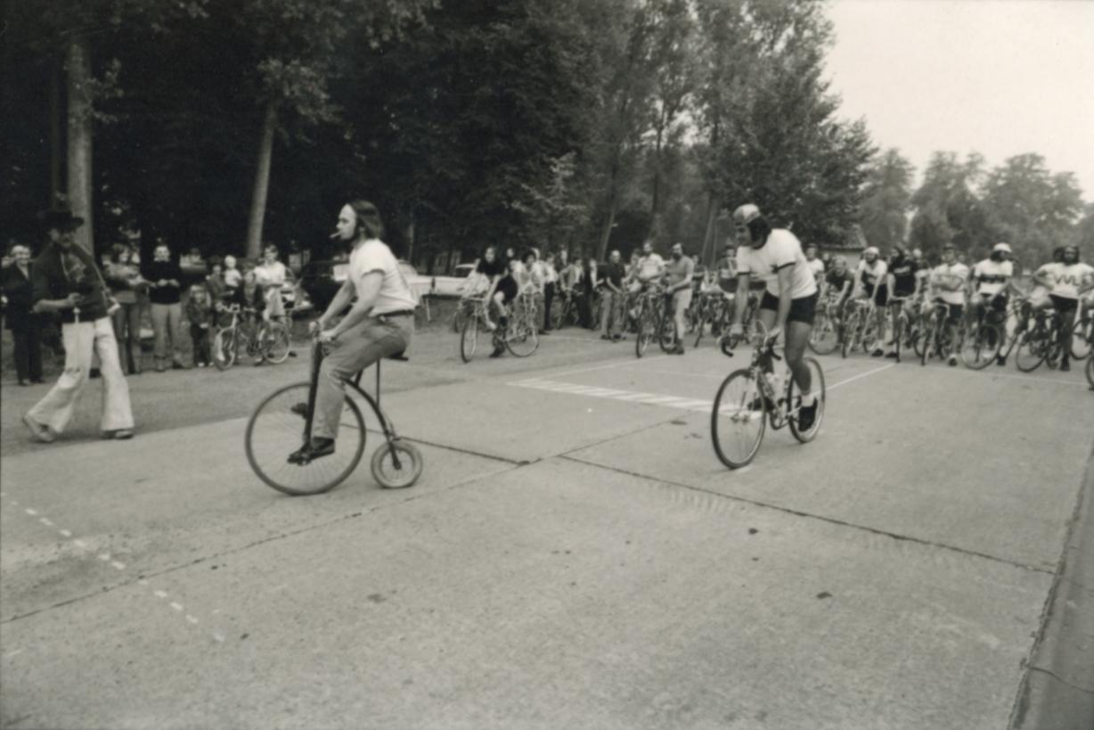 Herman J. Claeys op een fiets met een groot voorwiel en een klein achterwieltje en Paul Koeck op een gewone koersfiets,1971