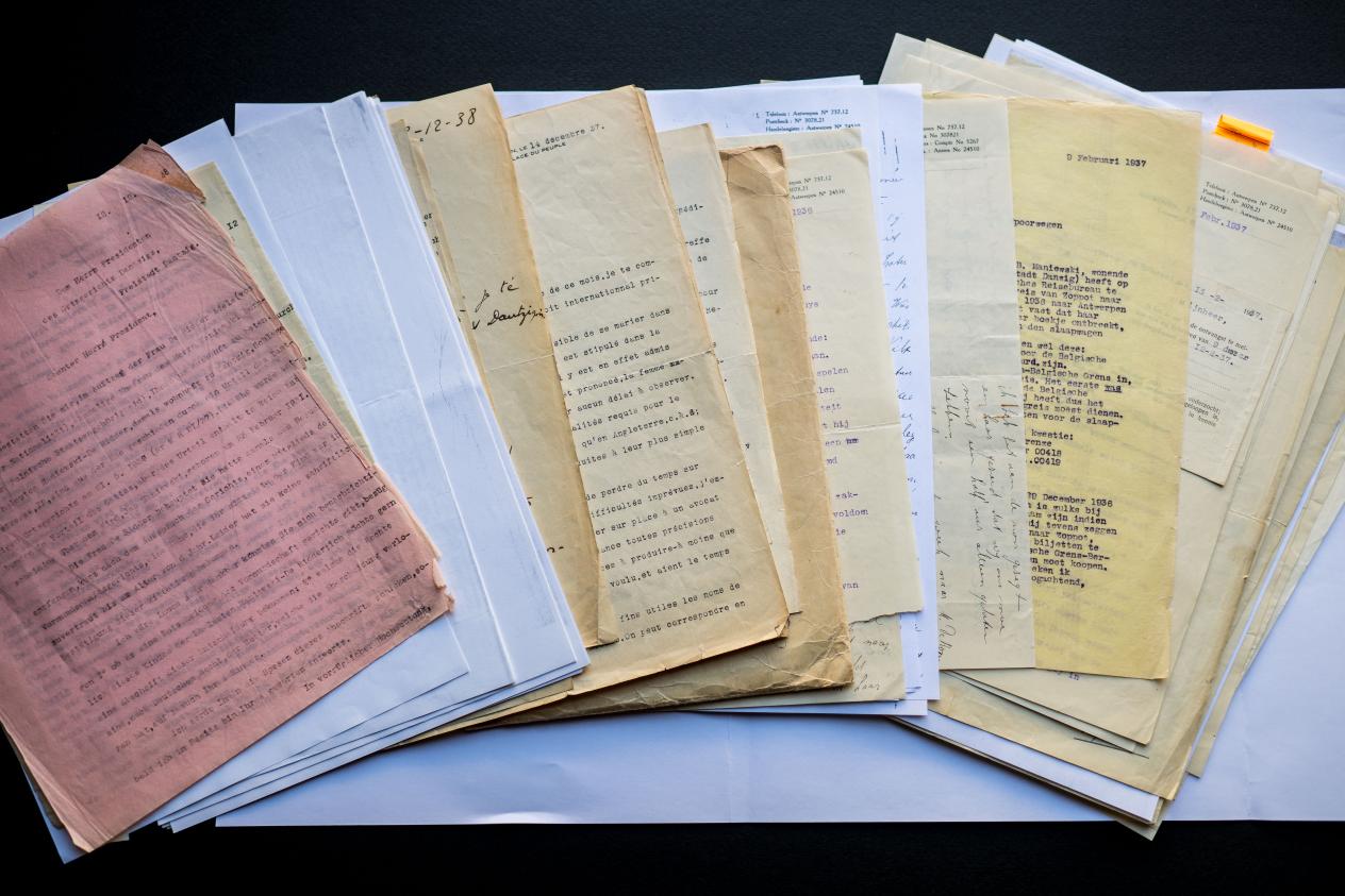 Verspreid over de tafel liggen verschillende documenten en mapjes die samen het dossier van de echtscheiding van Adele de Ridder vormen.