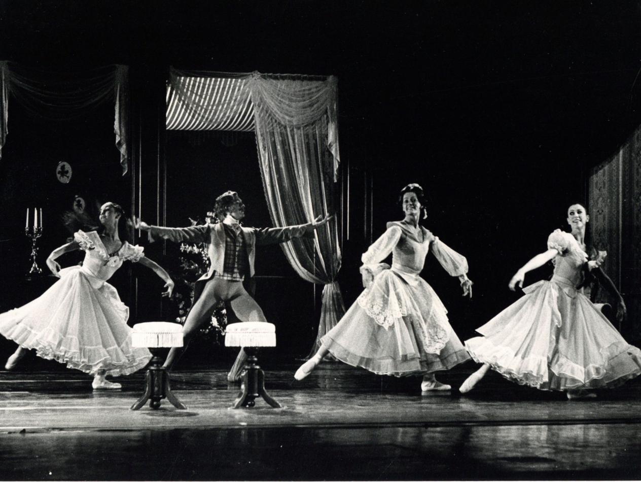 Foto van een balletopvoering met 4 dansers, 3 vrouwen en een man