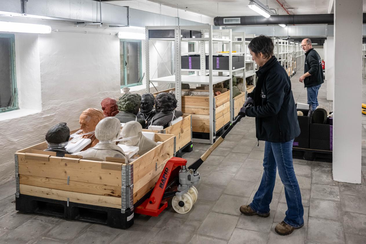 De beelden worden in grote houten kisten op een transpalet het Letterenhuis in gereden