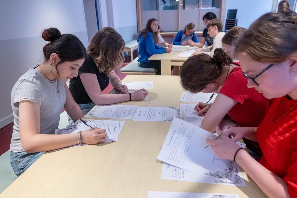 Vier meisjes zitten aan een tafel en schrijven een gedicht voor moederdag.