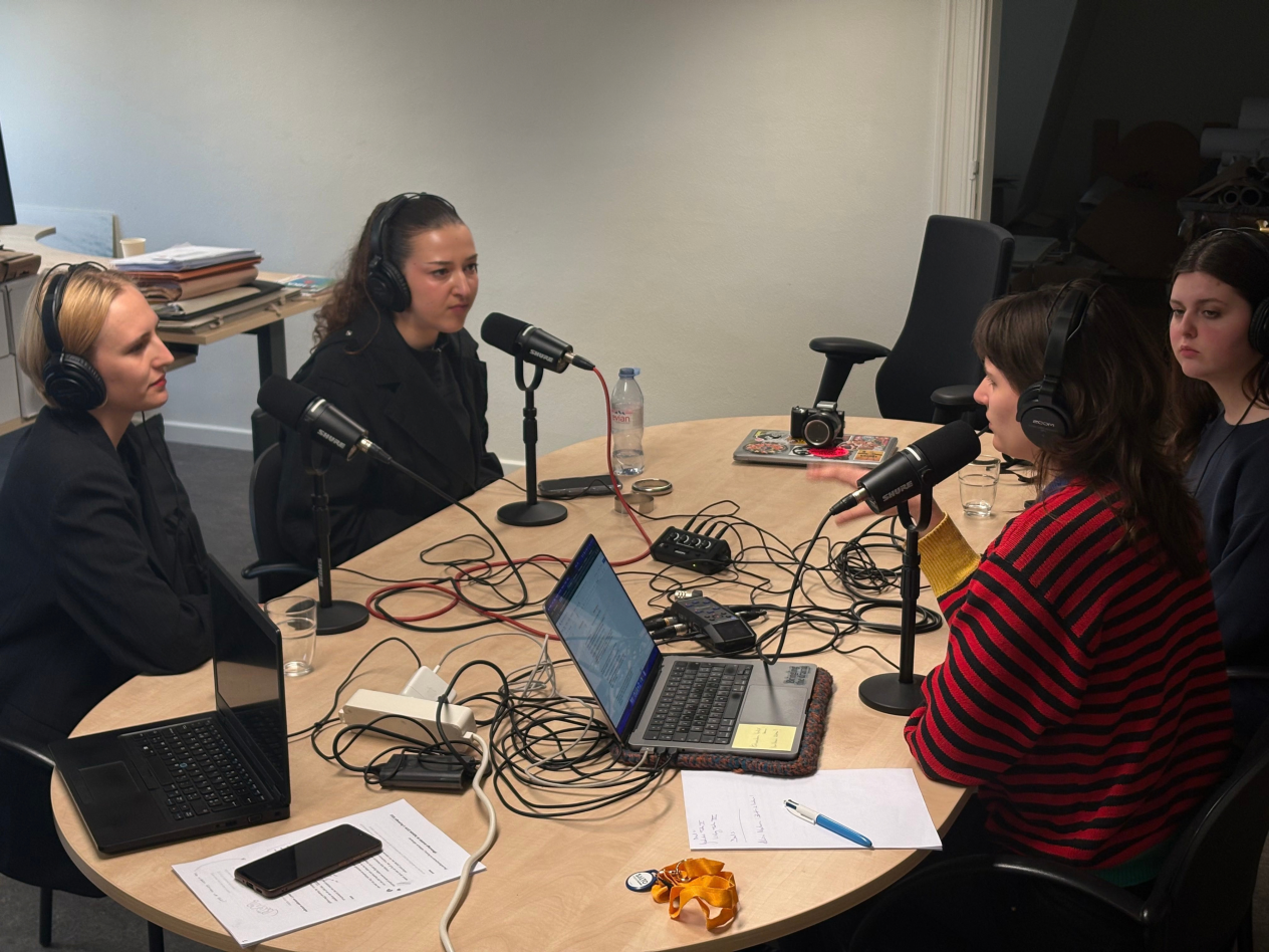 4 jonge studentes zijn in gesprek aan een tafel in het Letterenhuis, ze maken hierbij gebruik van het podcastmateriaal.