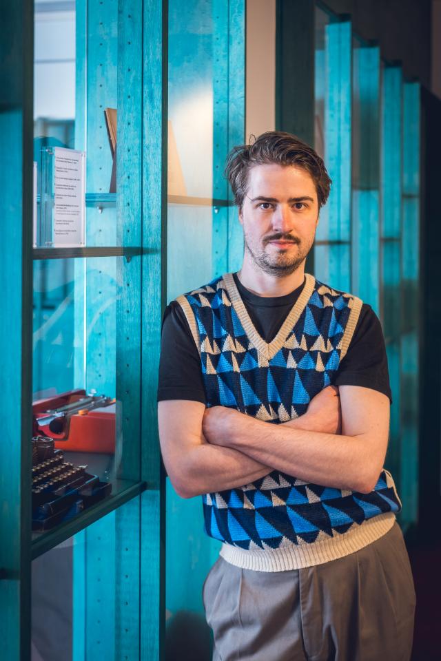 Portretfoto van Jonathan van der Horst bij de vitrinekasten in het Letterenhuis