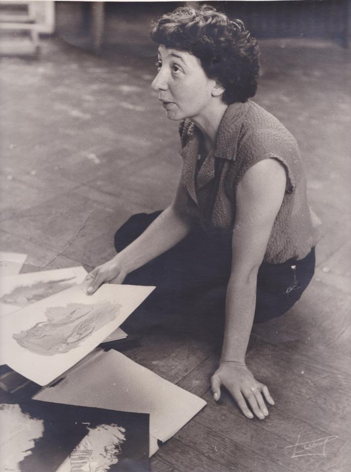 Zwartwitfoto van Jeanne Brabants die op de vloer zit met schetsen vast