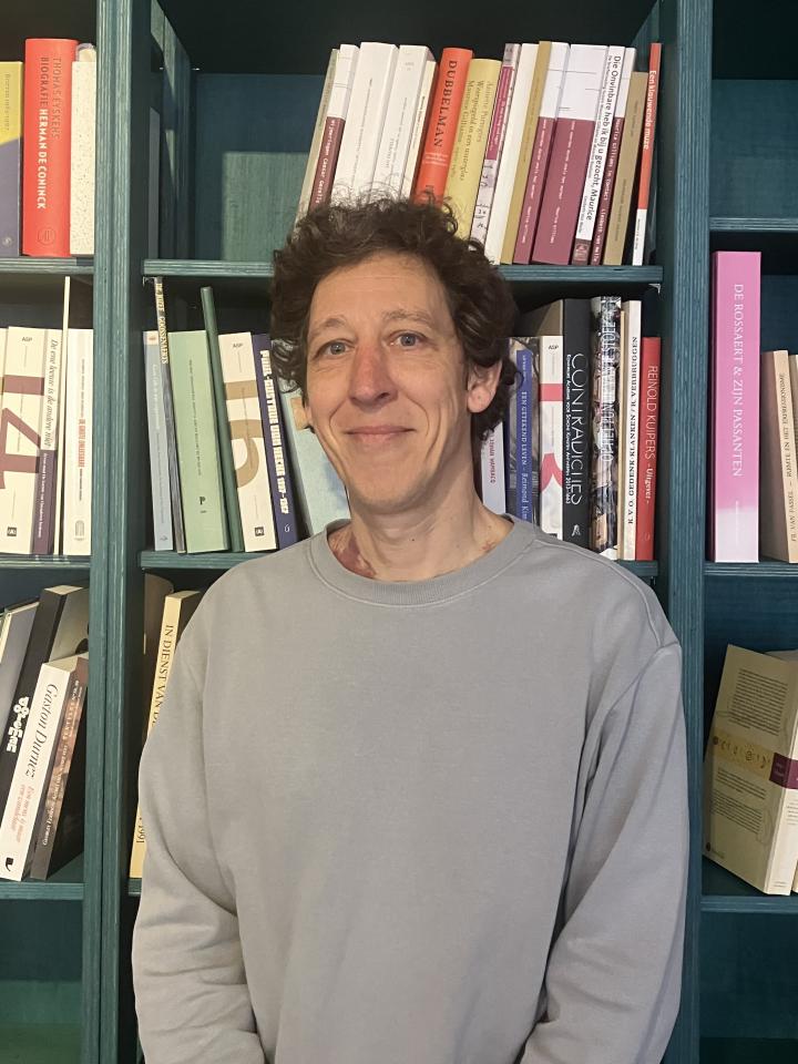Een portretfoto van Tom Mariën voor de boekenkast in de leeszaal van het Letterenhuis
