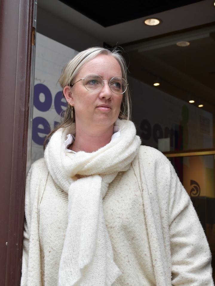 Portretfoto van Uus Knops, leunend tegen de grote inkomdeur van het Letterenhuis