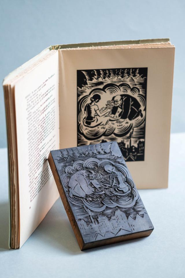 Houtblok met uitsnede van een man die knielt voor een dame. Erachter staat een opengeslagen boek met dezelfde illustratie erin gedrukt.