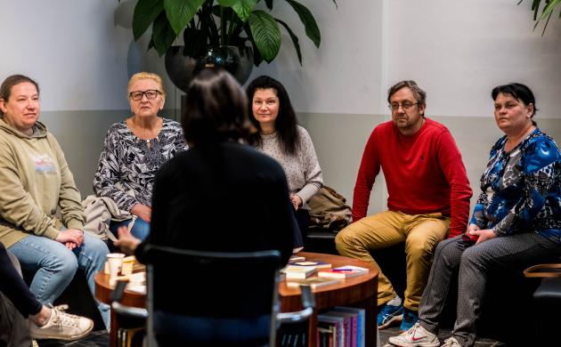 Een groep volwassenen luistert naar de samenleesbegeleider