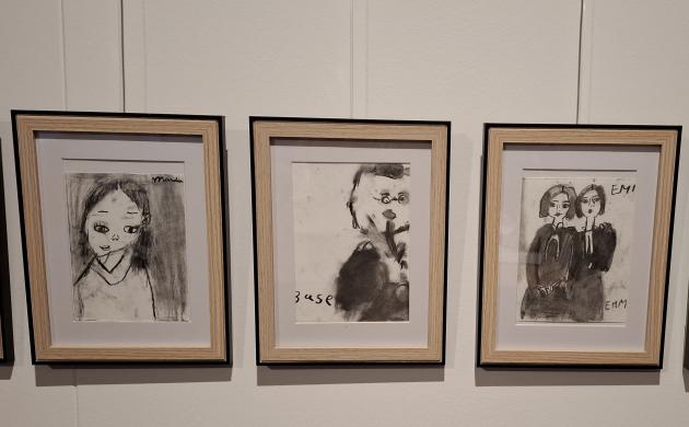 4 houten kaders aan de muur met auteursportretten in houtskool