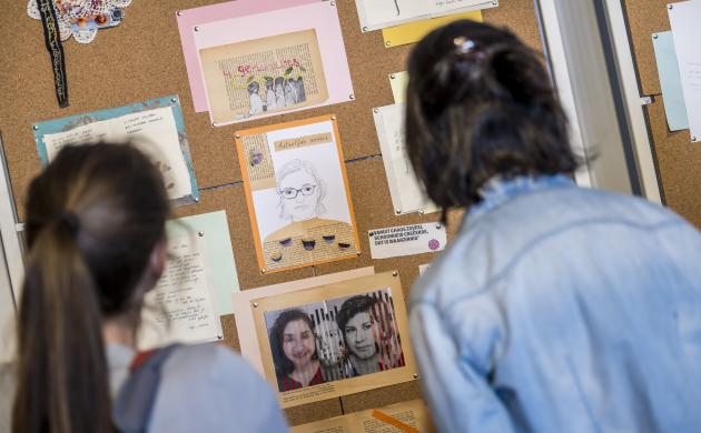 Twee vrouwen bewonderen enkele kunstwerken die gemaakt werden tijdens de workshopreeks Moederland