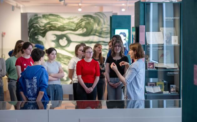 Een gids vertelt aan een groep leerlingen meer over de expo in de publieksruimte van het Letterenhuis.