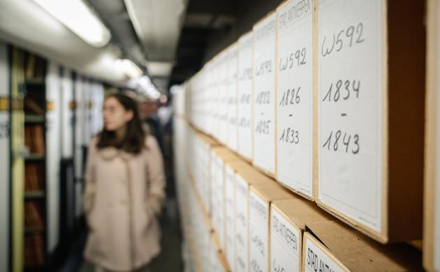 Foto van een bezoeker die een blik werpt op de archiefkasten in het depot