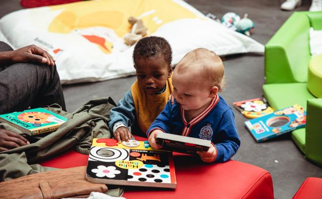 2 peuters kijken samen naar boekjes op een tafeltje