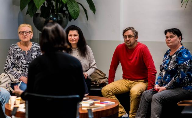 Een groep volwassenen luistert naar de samenleesbegeleider