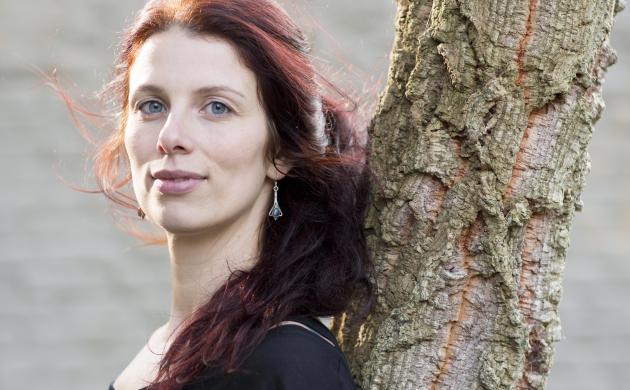 Portretfoto van Sien Volders tegen een boomstam leunend
