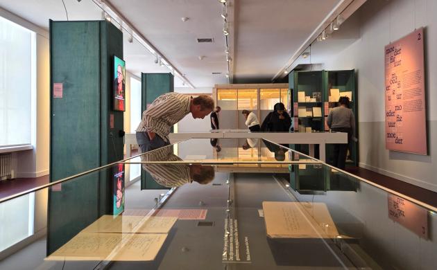 Bezoekers buigen zich over de vitrinekasten in de expo om de archiefstukken te bekijken