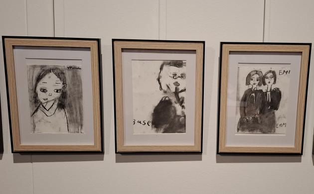 4 houten kaders aan de muur met auteursportretten in houtskool