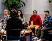 Een groep volwassenen luistert naar de samenleesbegeleider