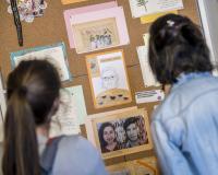 Twee vrouwen bewonderen enkele kunstwerken die gemaakt werden tijdens de workshopreeks Moederland